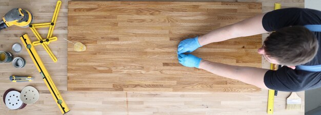 Carpenter works with tree on table, near tool