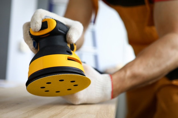 Carpenter works with tree with sander machine