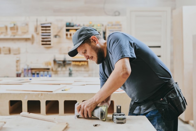 Carpenter works with wood in carpentry workshop Man doing woodwork professionally