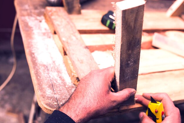 Photo the carpenter works with wood on his workspace