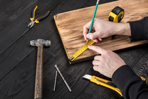 The carpenter works with wood on his workspace 