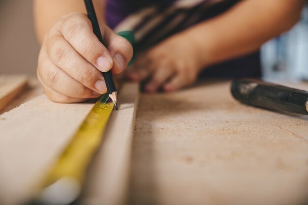 Carpenter in the workshop marks on wooden board in workshop