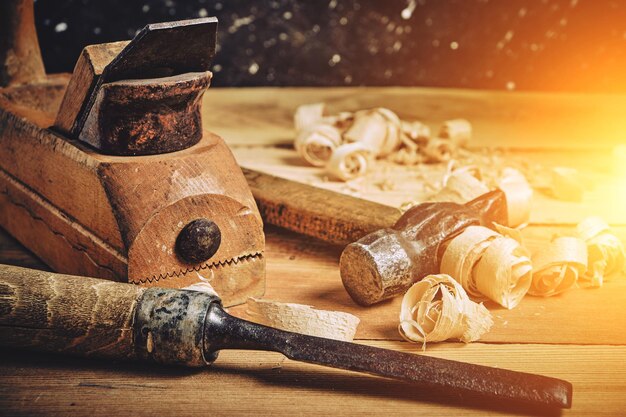 Carpenters tool kit hammer chisel and plane on a wooden background with shavings