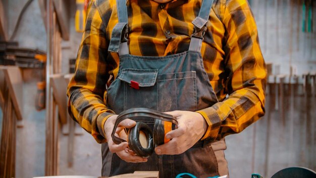 Carpentry indoors a man woodworker holding soundproof headphones