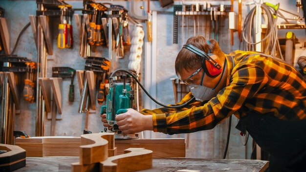 Carpentry indoors a man woodworker polishes the wooden detail in the workshop