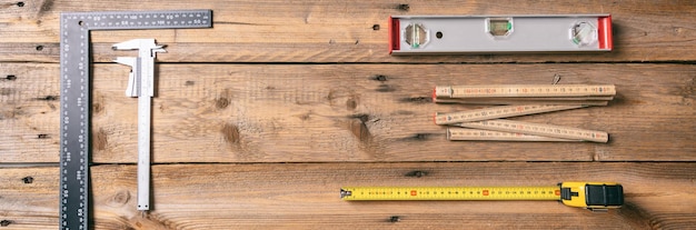 Photo carpentry measure tape spirit level and rulers on wooden background banner copy space top view