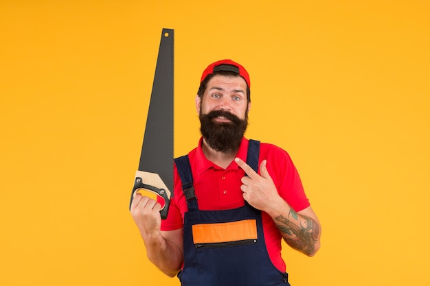 Carpentry workshop concept. Professional tools. Builder worker carpenter handyman hold saw yellow background. Man hold handsaw in hand. Carpentry works. Repair wooden objects. Carpentry service.