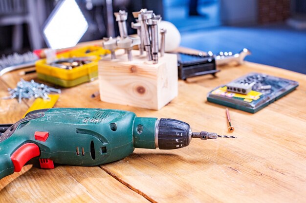 Carpentry workshop, drill and other tools lie on the table close up