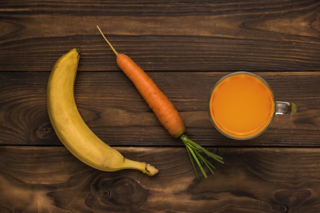 Banana di carote e un bicchiere di frullati su un tavolo di legno