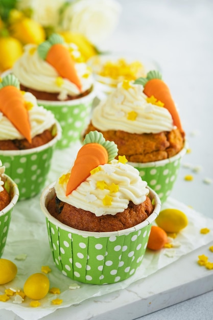 Carrot cake cupcakes for Easter Carrot cupcakes with cream cheese frosting decorated with tiny marzipan carrots on white background Happy Easter and spring holiday concept Holydays homemade dessert