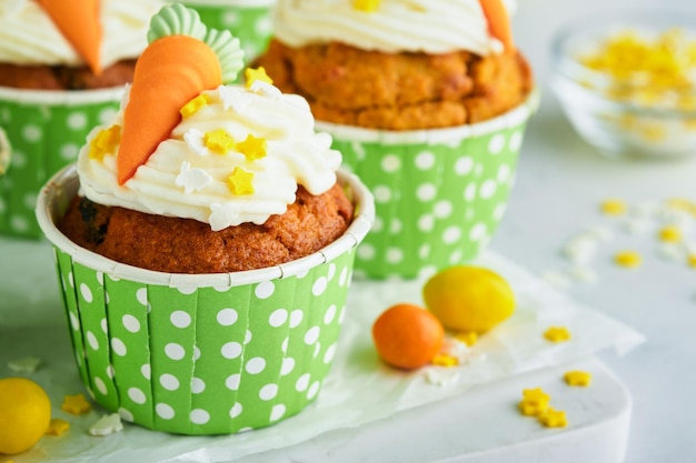 Carrot cake cupcakes for Easter Carrot cupcakes with cream cheese frosting decorated with tiny marzipan carrots on white background Happy Easter and spring holiday concept Holydays homemade dessert