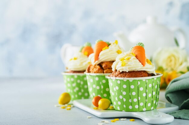 Carrot cake cupcakes for Easter Carrot cupcakes with cream cheese frosting decorated with tiny marzipan carrots on white background Happy Easter and spring holiday concept Holydays homemade dessert