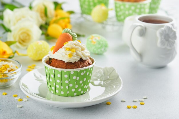 Carrot cake cupcakes for Easter Carrot cupcakes with cream cheese frosting decorated with tiny marzipan carrots on white background Happy Easter and spring holiday concept Holydays homemade dessert