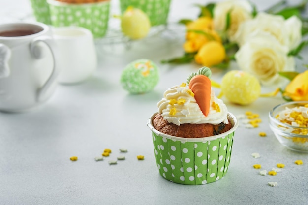 Carrot cake cupcakes for Easter Carrot cupcakes with cream cheese frosting decorated with tiny marzipan carrots on white background Happy Easter and spring holiday concept Holydays homemade dessert