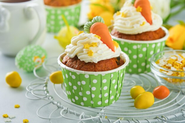 Carrot cake cupcakes for Easter Carrot cupcakes with cream cheese frosting decorated with tiny marzipan carrots on white background Happy Easter and spring holiday concept Holydays homemade dessert