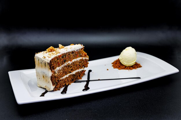 Carrot Cake op een witte plaat met ijs op een zwarte achtergrond