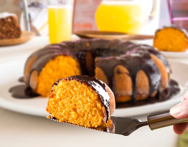 Carrot cake with chocolate and slice on the table.