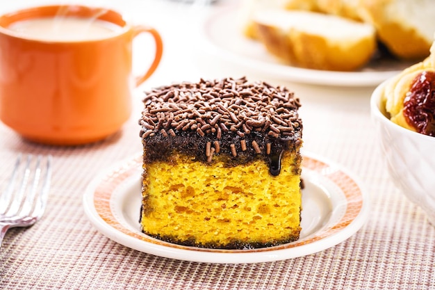 Carrot cake with chocolate sprinkles served with coffee with milk and toasted bread typical afternoon sweet made in Brazil