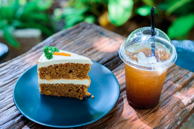 庭の木製テーブルの上のコーヒーとキャロットケーキ