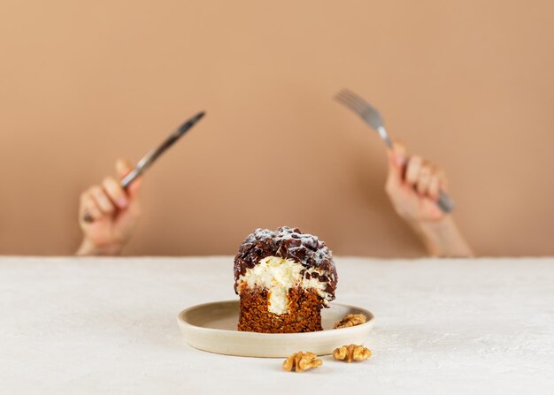 カーロットケーキクリームチーズチョコレートナッツフォークとナイフで手を握る