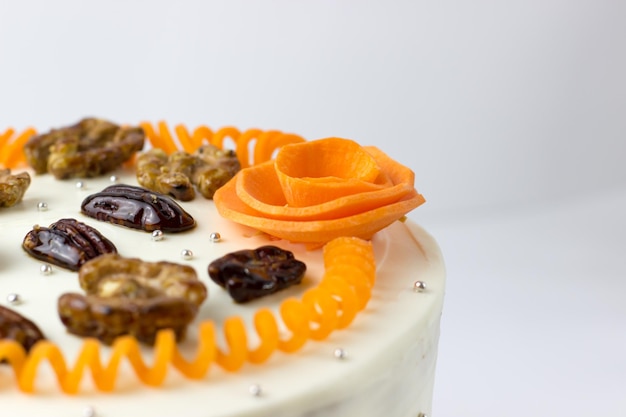 Carrot cake with cream cheese decorated with nuts and carrots