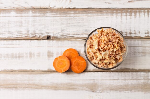 Carrot chips from juicy slices in a bowl on a wooden background