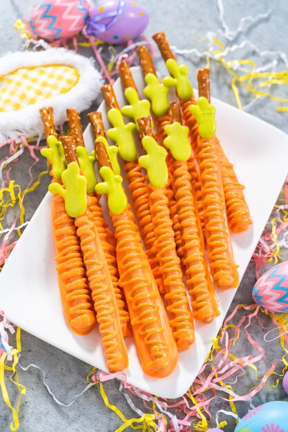 Carrot chocolate-covered pretzels on a white serving plate for the Easter table.