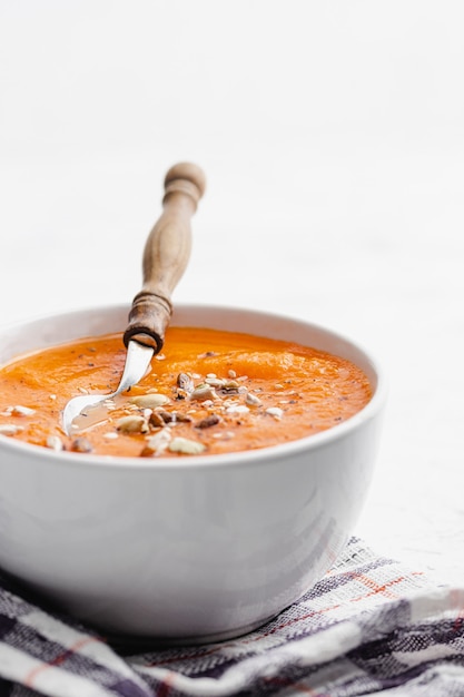 Carrot cream soup in a white bowl with cloth napkin