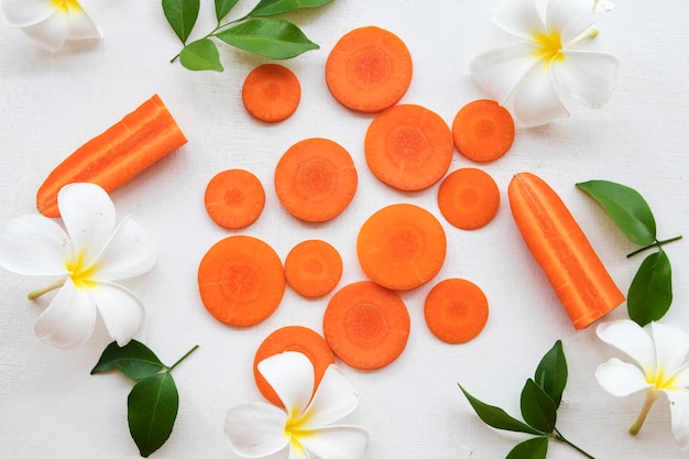 carrot flowers frangipani arrangement flat lay style