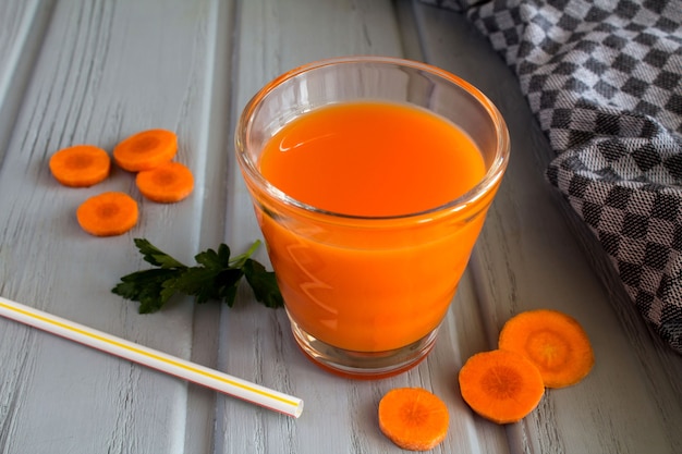 Carrot juice in the glass on  the grey  wooden  surface