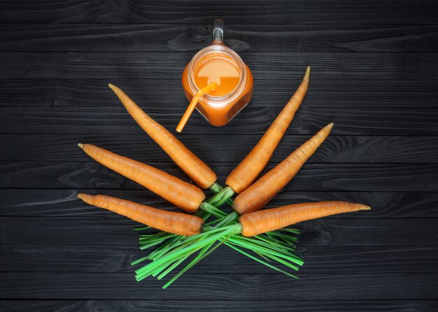 Succo di carota in un barattolo di vetro con carote fresche