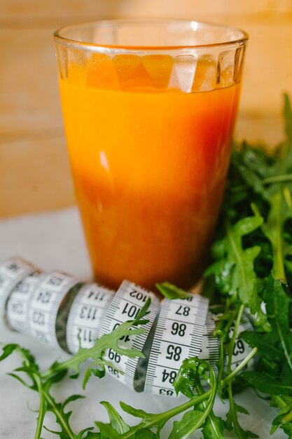 Foto succo di carota in un bicchiere con nastro e lattuga