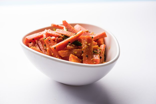 Carrot pickle or gajar ka achar or loncha in hindi. served in a bowl over moody background. selective focus