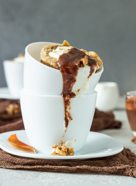 Carrot or pumpkin mug cupcake with whipped cream, caramel sauce and walnuts in a white ceramic mug. 