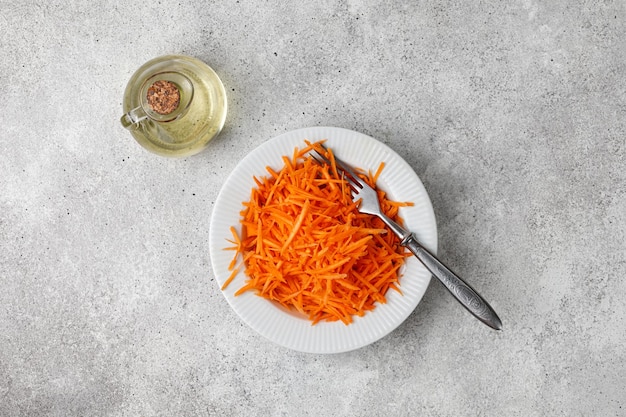 Carrot Salad with chopped carrot in a white bowl with fork Diet food concept Detox Grey background