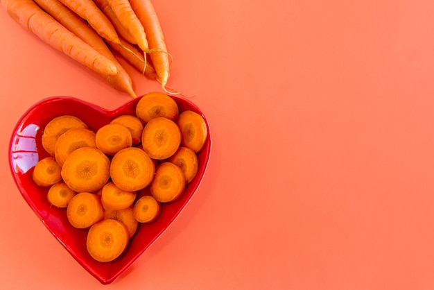 Carrot slices and strips on a table with an orange background.