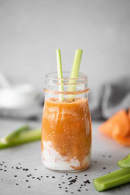 Frullato di carote con panna acida e semi di sesamo in una bottiglia di vetro