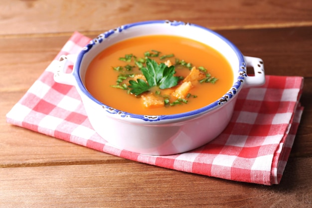 Carrot soup in bowl on wooden background