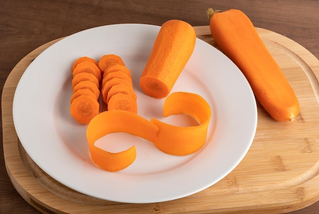 Carrot on a white plate on a wooden board ingredient food preparation