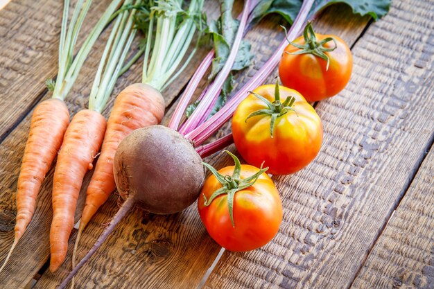 Carrots, beetroot and tomatoes just picked in the garden on wooden boards. Fresh vegetables.