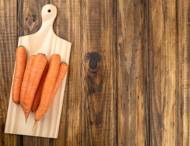 Carrots over a board on a wooden table with copy space.