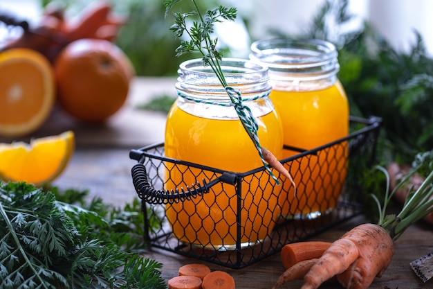Carrots and carrot juice with orange ginger in a glass jar in a metal basket