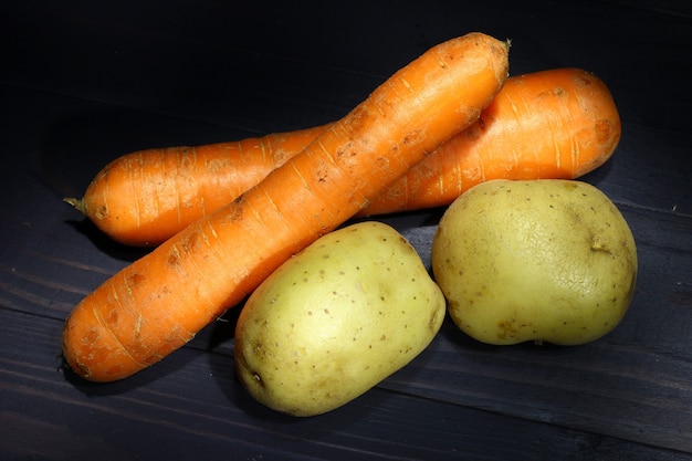 Carrots and potatoes on a dark background