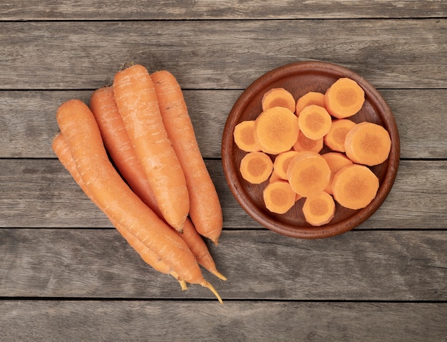 Carrots and slices on a plate over wooden table.