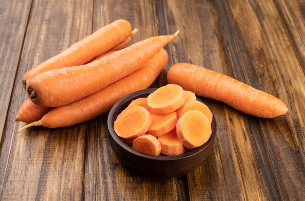 Carrots and slices on a plate over wooden table.