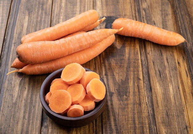 Carrots and slices on a plate over wooden table