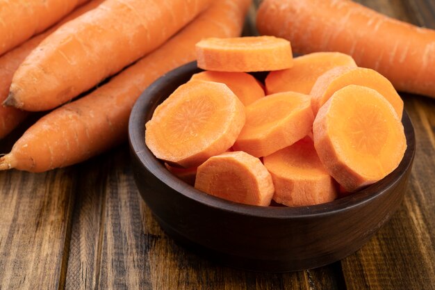 Carrots and slices on a plate over wooden table.