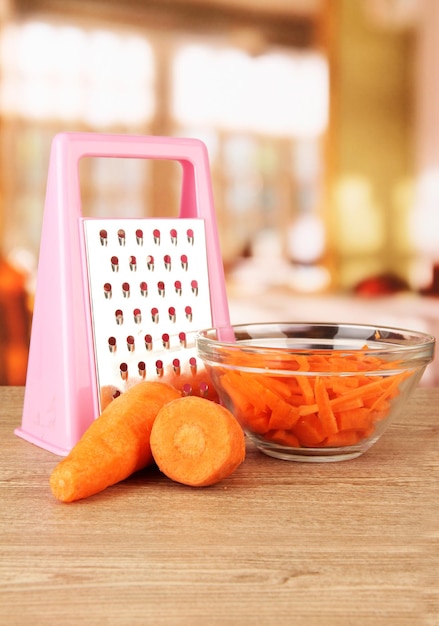 Carrots with grater on table in kitchen