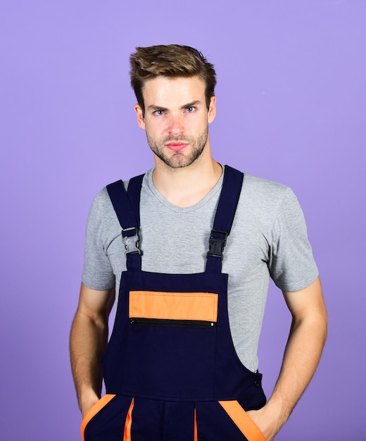 Carry out repairs man builder in work clothes professional repairman man build house building and construction worker purple background skilled architect repair and fix turnkey project