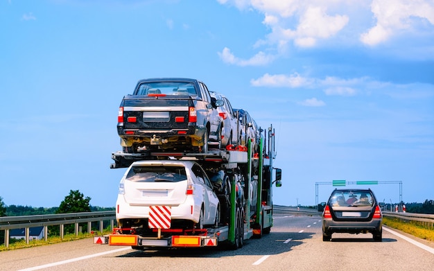 Photo cars carrier truck in road or highway of poland. lorry transporter at logistics work. trailer with cargo car drive. delivery for transport export industry. heavy hauler. haul vehicle. auto haulage.